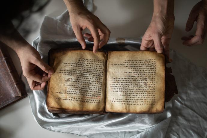 A medieval manuscript lies open and unwrapped on a table