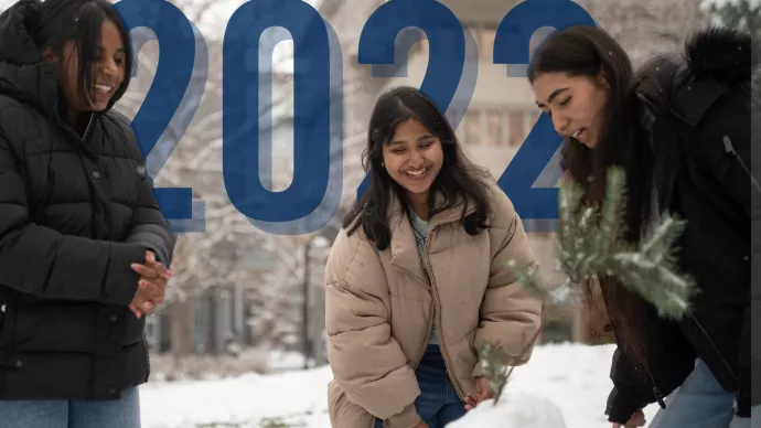 The numbers 2022 appear in the background as three students play in the snow.