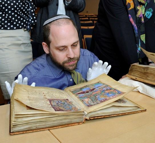 Adam Cohen wearing white gloves looking at an old book
