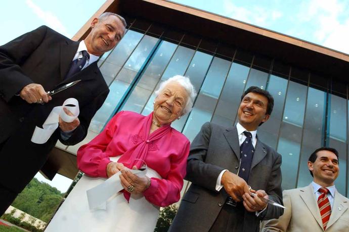 Hazel McCallion standing in front of a building holding a ribbon beside Ian Orchard.
