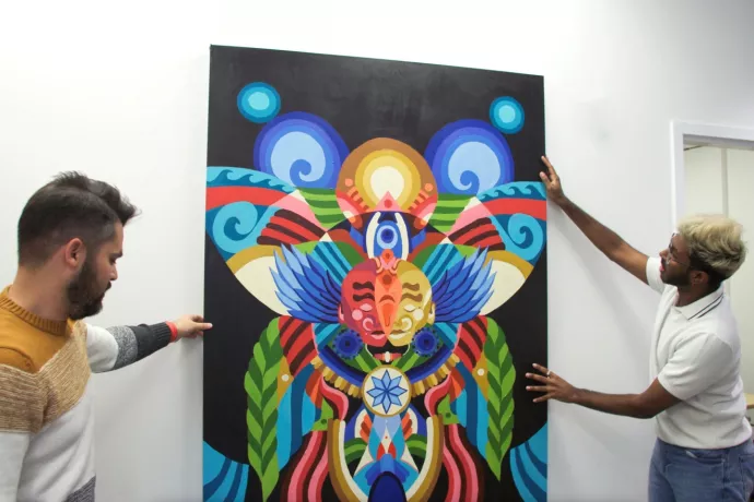 Michael Gomez and Benji Jacob adjust a large painting on a wall