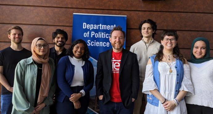 Group photo of students and professor with a "Department of Political Studies" banner behind them