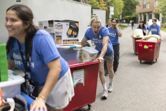 Staff and volunteers push carts while helping students move-in to residence.