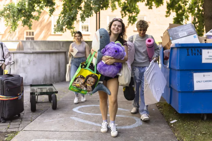 A student carries their belongings on a path.
