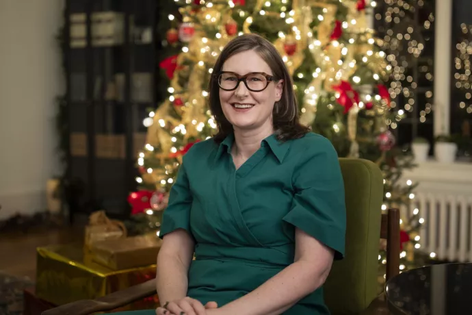 Alexandra Gillespie sits in front of a festively decorated Christmas tree. 