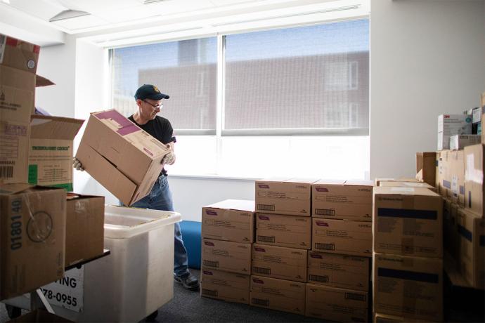 Man moving a box in a room filled with neatly stacked boxes