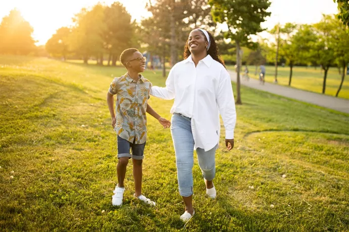 Thereasa Gordon and her son Romeo walk in the grass in a park, laughing together.