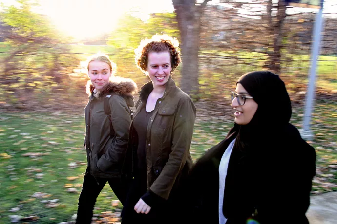 Fiona Rawle walking with two students on campus near trees