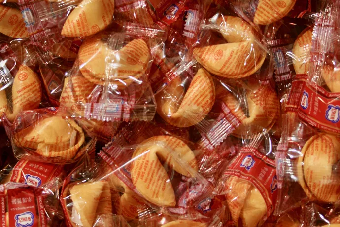 multiple fortune cookies in plastic wrappers in a pile