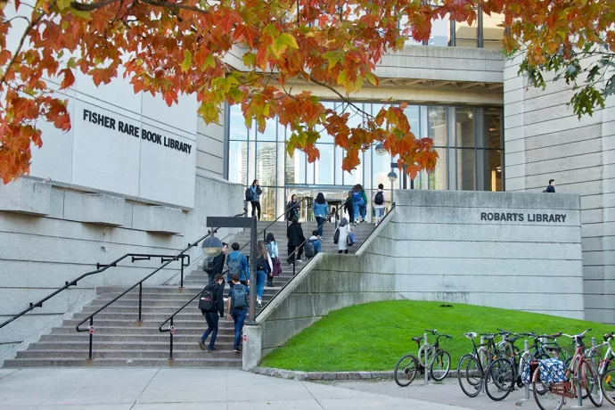 Photo of Robarts Library, grey concrete building with wide staircase leading up to glass entrance, with students walking up the stairs.