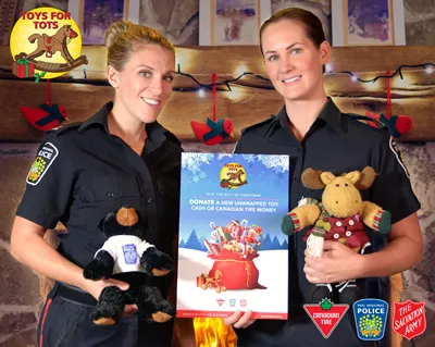 Peel Police constables hold stuffed animals in front of Toys for Tots logo