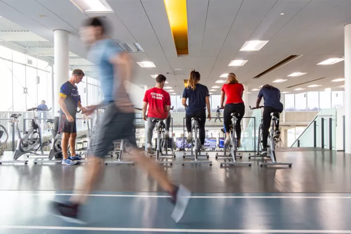 Row of people on ellipticals with person running in foreground