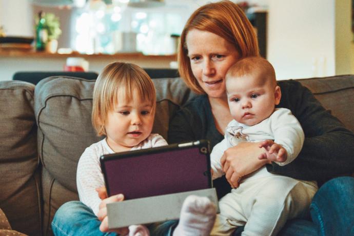 A woman and two children use a tablet device