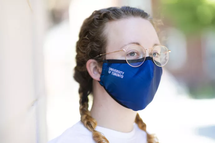 Woman wearing blue fabric mask with University of Toronto embroidered on it