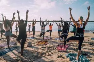 A group of people practice yoga on a beach.