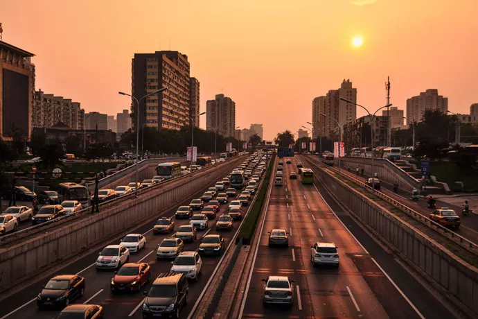 Cars on divided highway, three lanes each side, in an orange sunset