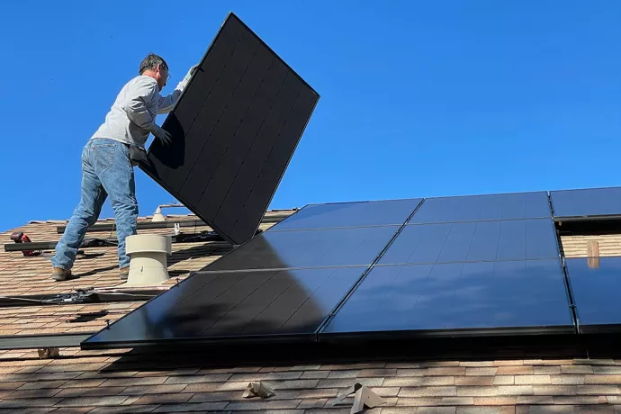 A man stands on a roof installing solar panels