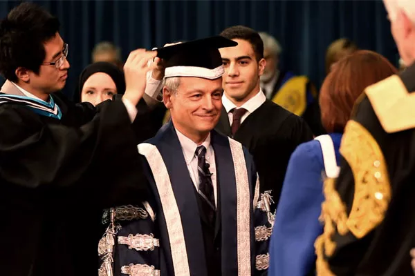Students Jerry Jien, Katharine Ball and Mohamed Farid Abdel Hadi robe Meric Gertler in the ceremonial regalia of the president as Governing Council Chair Judy Goldring and Chancellor Michael Wilson look on