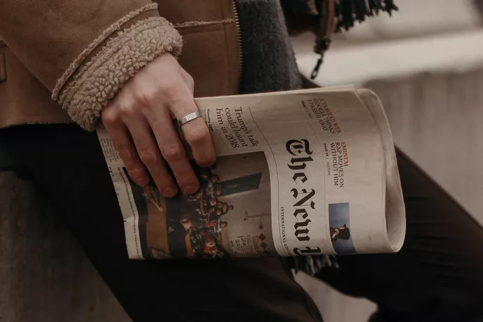 Man holding folded New York Times newspaper