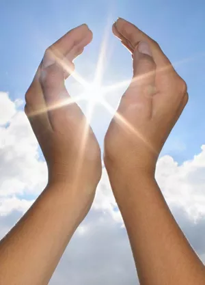 Image of sun shining through gap in hands
