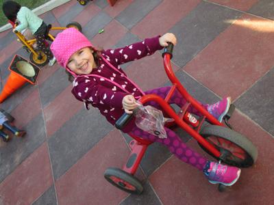 young girl on red tricycle
