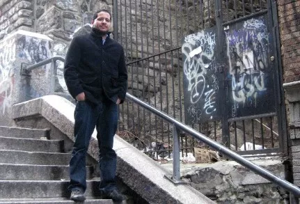 man wearing black standing on steps with graffiti wall