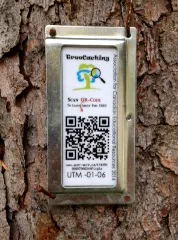 metal tag with black and white QR code nailed to tree bark