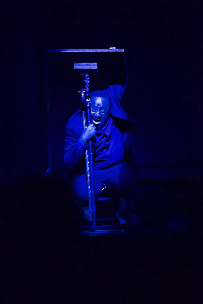 Actor on stage, hiding under a podium in low light