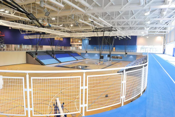Basketball court with blue track running above it, blue walls and blue bleachers on either side of the court