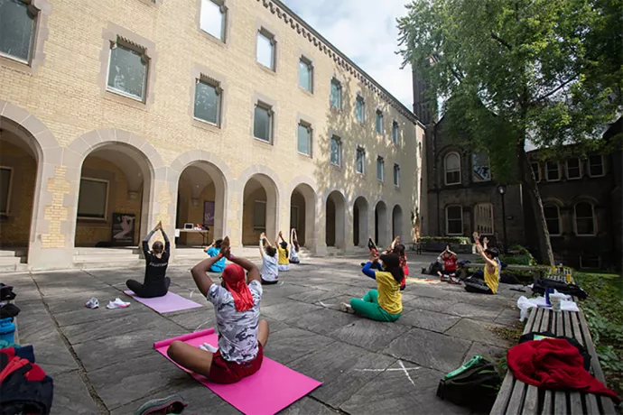 People physically distanced outside building doing yoga