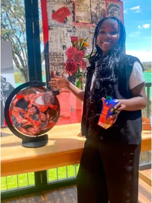 Paris Ouma stands in front of a globe that has been painted multiple colours