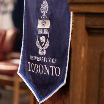 University of Toronto crest on flag draped over wooden podium in Convocation Hall