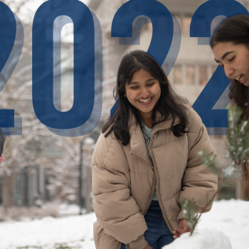 The numbers 2022 appear in the background as three students play in the snow.