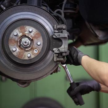 A car mechanic changes the brake disc of a Range Rover Evoque in a garage