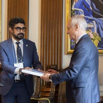Vikram Chadalawada hands a document to U of T President Meric Gertler 