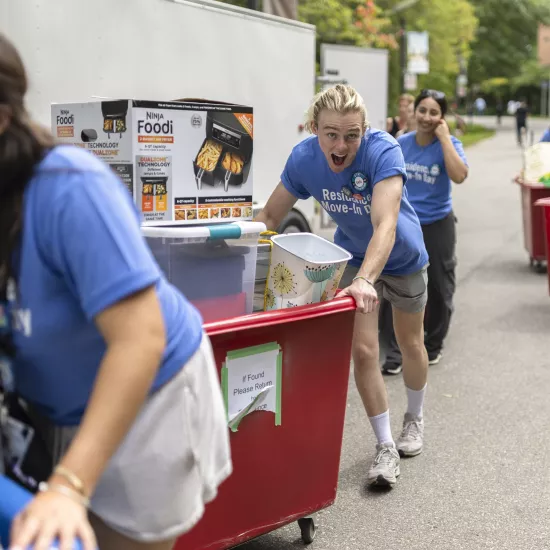 Staff and volunteers push carts while helping students move-in to residence.