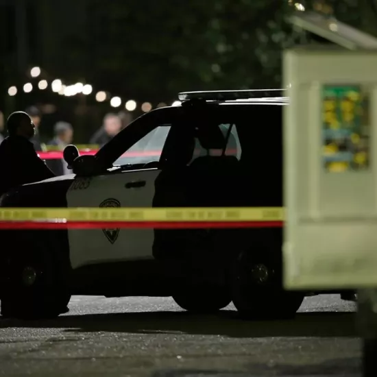 Police vehicle at crime scene with yellow crime scene tape in foreground