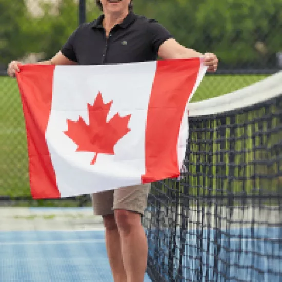 Alison Dias on a tennis court holding a Canadian flag