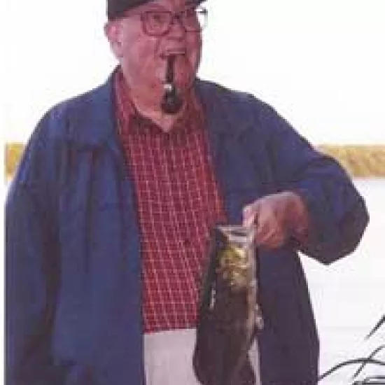 Professor Emeritus Peter Silcox smoking a pipe and holding a fish by the gills.
