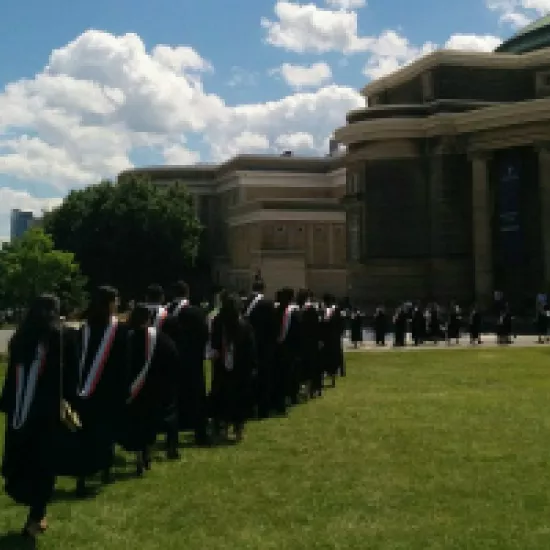people in graduation gowns walk across a lawn