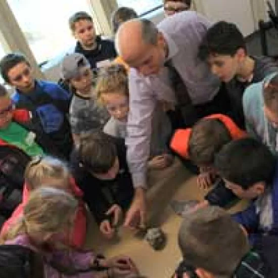 Ulrich Krull shows a crowd of elementary students a piece of meteorite