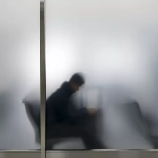 man sitting behind a semi-opaque window