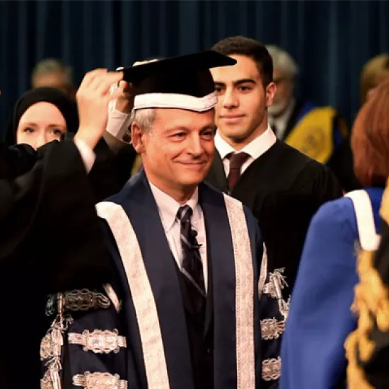 Students Jerry Jien, Katharine Ball and Mohamed Farid Abdel Hadi robe Meric Gertler in the ceremonial regalia of the president as Governing Council Chair Judy Goldring and Chancellor Michael Wilson look on