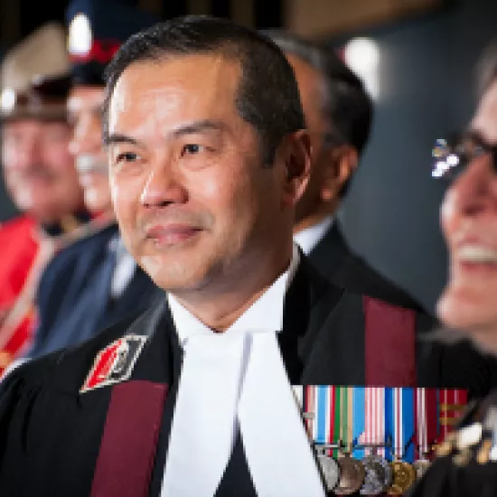 judge albert wong wearing military medals and robes with an RCMP officer in the background