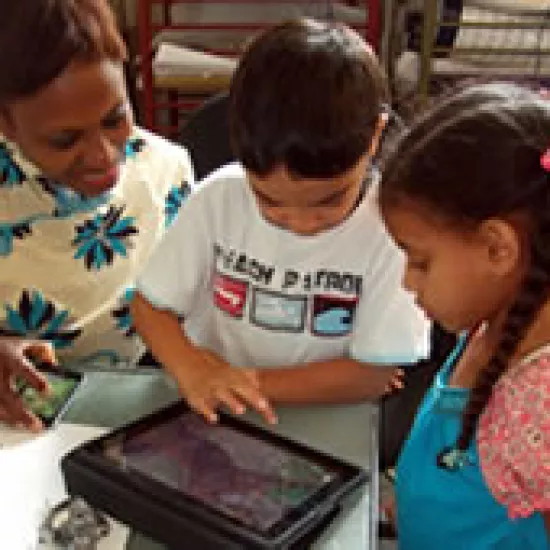 Three children gathered around, looking at a tablet.