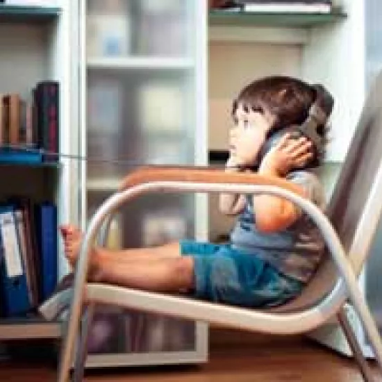 Toddler sits in chair and wears large stereo headphones