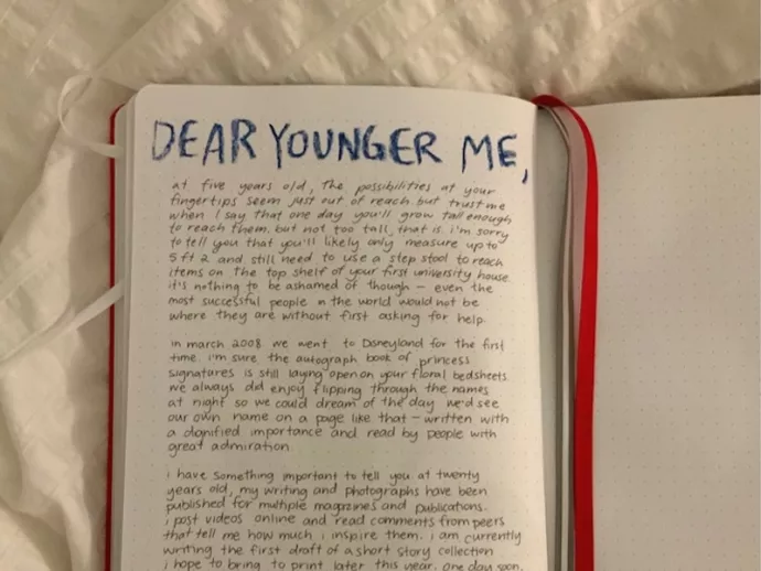A diary open to a page that reads "Dear Younger Me," followed by a long blurb of indistinguishable text.