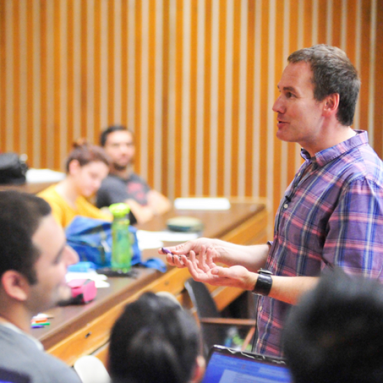Professor teaching in a lecture hall of students.