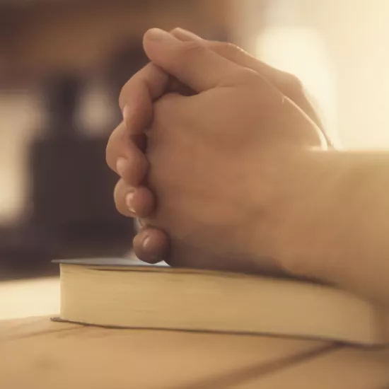 Praying hands on a book.
