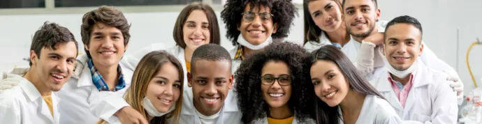 Group of students smiling in white lab coats